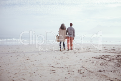 Couple holding hands while walking by the beach