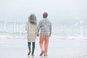 Couple holding hands while walking by the beach