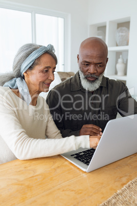 Couple using laptop on table inside a room