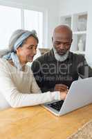 Couple using laptop on table inside a room