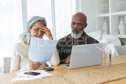 Couple discussing papers and using laptop inside a room