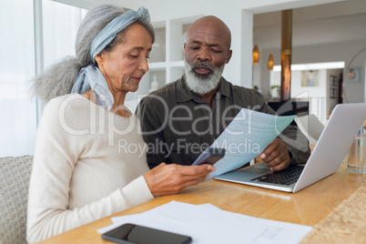 Couple discussing papers and using laptop inside a room