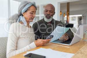 Couple discussing papers and using laptop inside a room