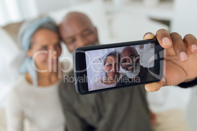 Couple sitting on a couch inside a room while taking a picture