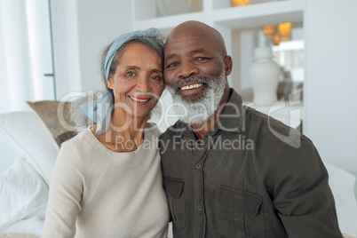 Couple smiling while sitting on a couch inside a room
