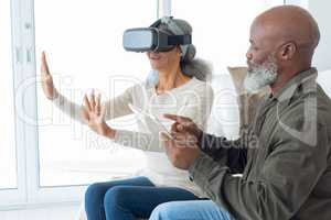 Couple using digital devices while sitting inside a room