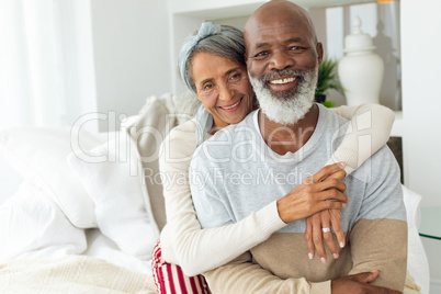 Couple sitting inside a room smiling.