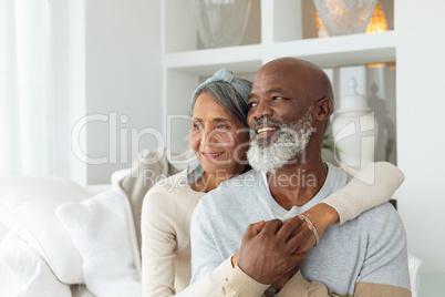 Couple sitting inside a room smiling.