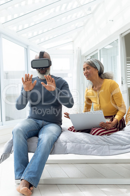 Couple sitting on a bed while using digital devices