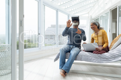 Couple sitting on a bed while using digital devices