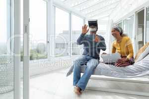 Couple sitting on a bed while using digital devices