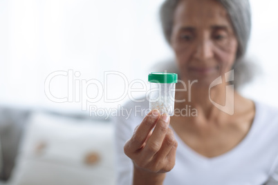 Woman sitting on couch while holding a small pill bottle