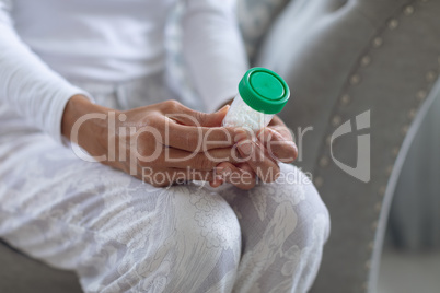 Woman sitting on a couch while holding a small pill bottle