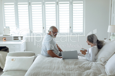 Couple sitting on bed inside a room