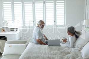 Couple sitting on bed inside a room