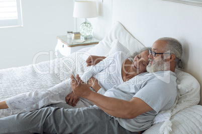 Couple lying in bed and watching digital tablet