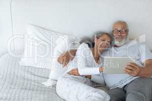 Couple lying in bed and watching digital tablet