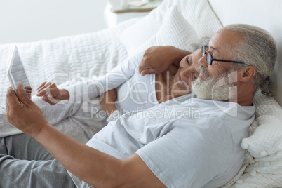 Couple lying in bed and watching digital tablet