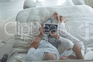 Couple lying in bed and watching digital tablet