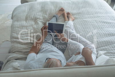 Couple lying in bed and watching digital tablet