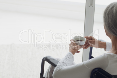 Woman on wheelchair drinking coffee