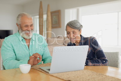 Couple using laptop on table inside a room