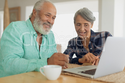 Couple using laptop on table inside a room