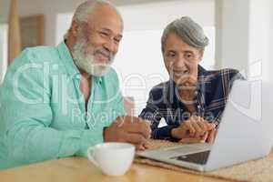Couple using laptop on table inside a room