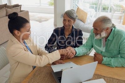 Man shaking hands with financial adviser while sitting beside wife