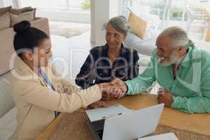 Man shaking hands with financial adviser while sitting beside wife