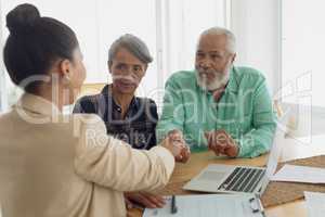 Man shaking hands with financial adviser while sitting beside wife