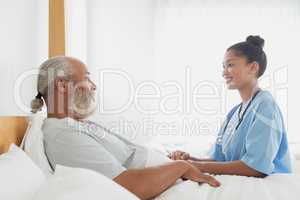Healthcare worker talking with old man in bed