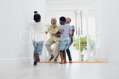 Children running towards an old couple by the door