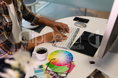 Male graphic designer working on computer at desk in office