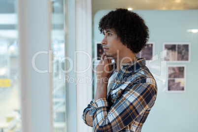 Male graphic designer looking through window