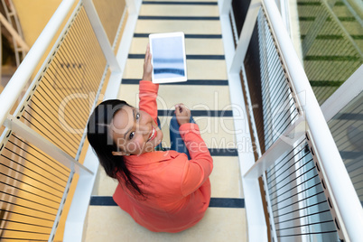 Businesswoman holding digital tablet on stairs