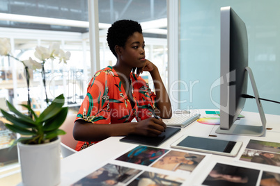 Female graphic designer working on graphic tablet at desk