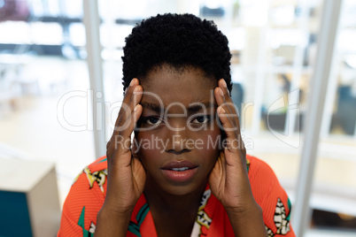 Stressed female graphic designer sitting at desk in office