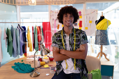 Male fashion designer sitting with arms crossed in design studio