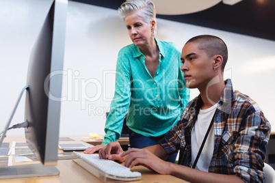Male and female graphic designers working together on computer at desk