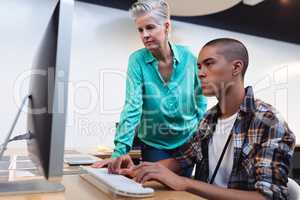 Male and female graphic designers working together on computer at desk