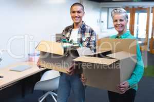 Male and female executives carrying cardboard boxes in office