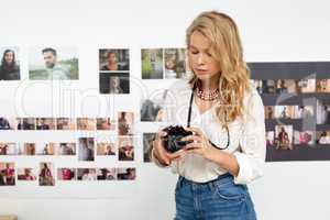 Female graphic designer reviewing photos on digital camera in office