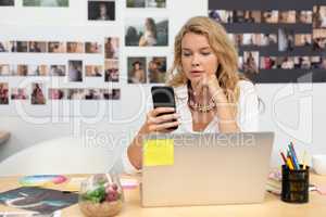 Female graphic designer using mobile phone at desk