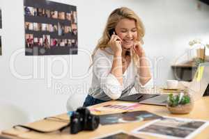 Female graphic designer talking on mobile phone at desk