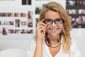 Happy female graphic designer adjusting her spectacle in office