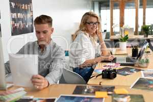 Male and female graphic designers working together at desk