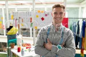 Male fashion designer standing with arms crossed in design studio