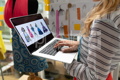 Female fashion designer using laptop in design studio