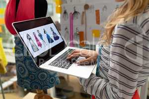 Female fashion designer using laptop in design studio